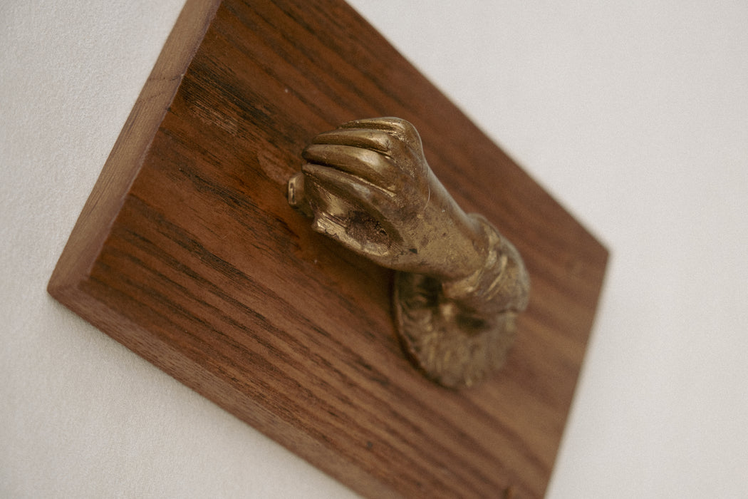 Vintage brass hand door knocker on wood