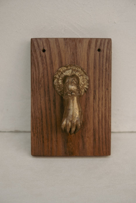 Vintage brass hand door knocker on wood